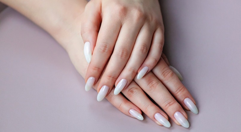 Model woman showing light white nude shellac manicure on the long nails