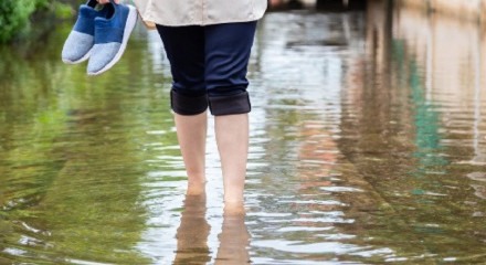 Imagem ilustrativa de pessoa andando em meio a enchente sem proteção