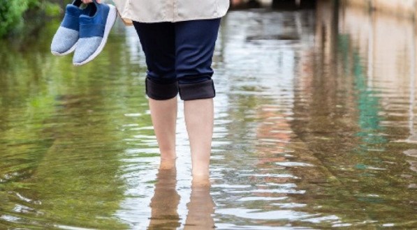 Imagem ilustrativa de pessoa andando em meio a enchente sem proteção