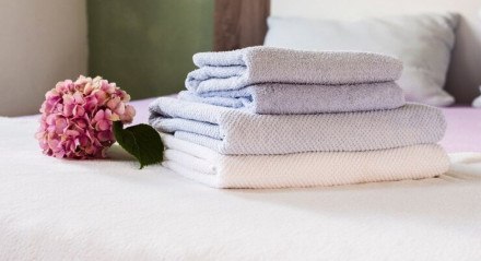 Imagem ilustrativa de toalhas macias e cheirosas sobrada em cima da cama