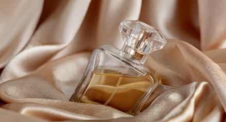 Garrafa de vidro de perfume em fundo de seda dourada