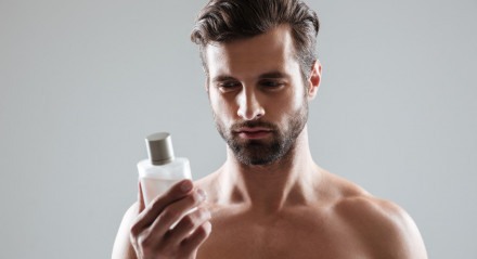 Homem olhando para um frasco de perfume isolado
