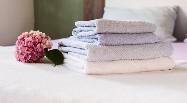 Imagem ilustrativa de toalhas macias e cheirosas dobradas em cima da cama