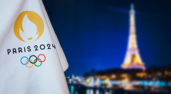 Na imagem, bandeira das Olimpíadas de Paris 2024 em frente à Torre Eiffel 