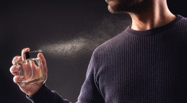 Man Spaying Perfume on Dark Background