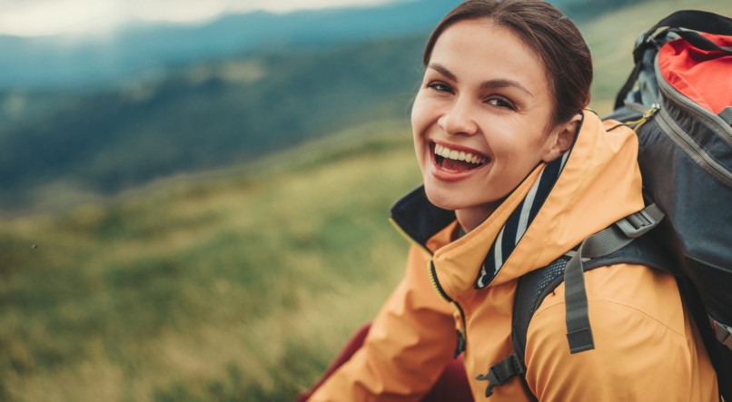 Delighted young woman resting on the slopes of the mountain while feeling happy
