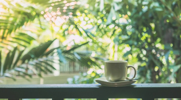 Imagem ilustrativa para mensagem de bom dia mostrando uma xícara de café apoiada sobre uma varanda