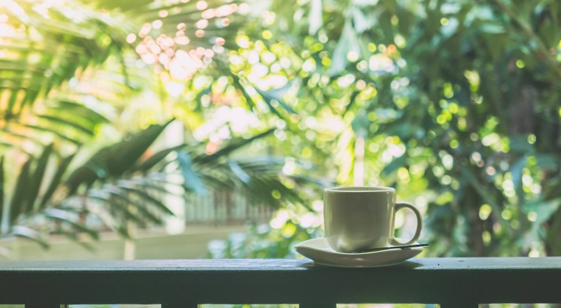 Imagem ilustrativa para mensagem de bom dia mostrando uma xícara de café apoiada sobre uma varanda