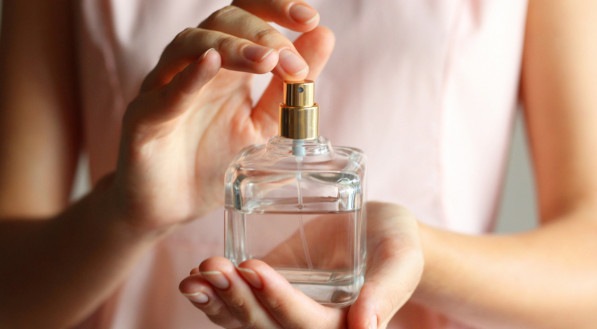 Imagem ilustrativa de uma mulher segurando perfume