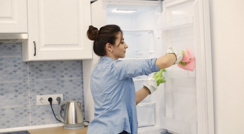 Imagem ilustrativa de mulher mostrando como limpar geladeira