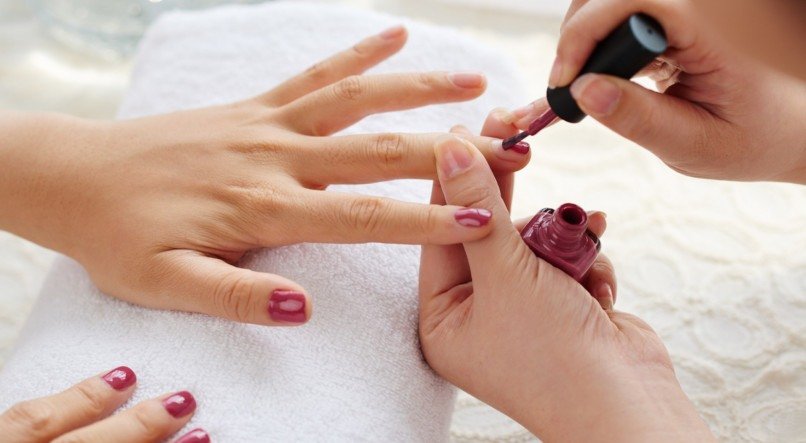 Master applying polish on fingernails on woman