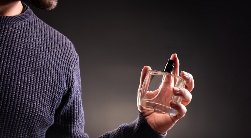 Man Holding Perfume Bottle on Dark Background
