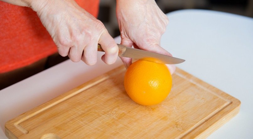 Pessoa retirando casca de laranja. 