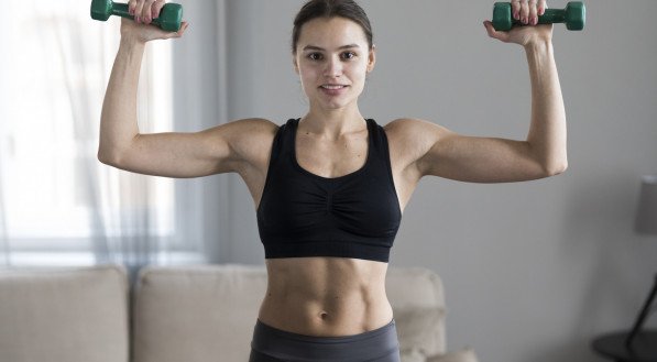 Imagem ilustrativa: mulher praticando muscula&ccedil;&atilde;o com halteres. 