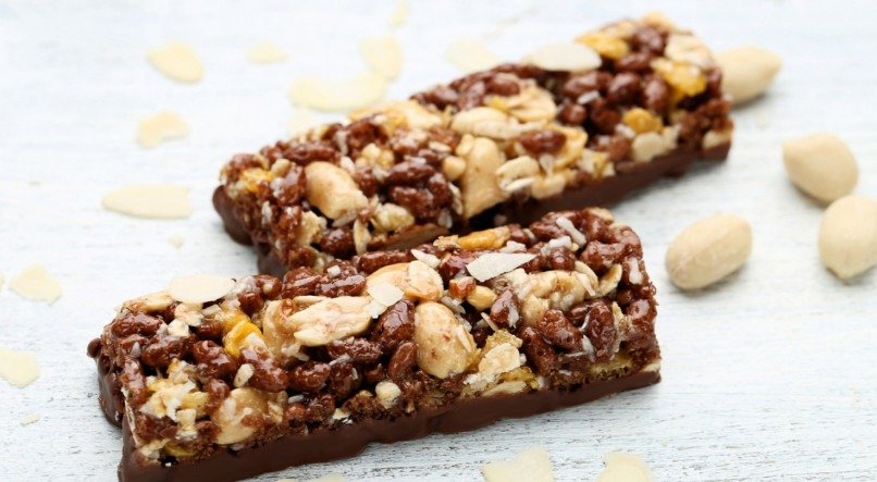 Tasty chocolate granola bars with nuts on wooden table