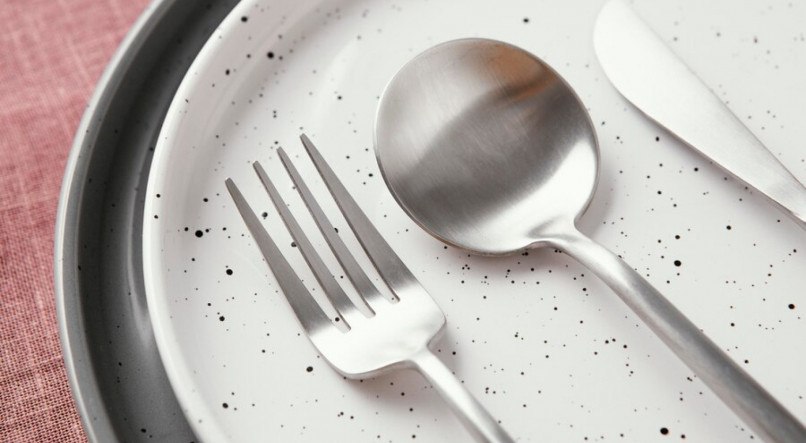 Imagem ilustrativa de talheres de prata sobre a mesa

