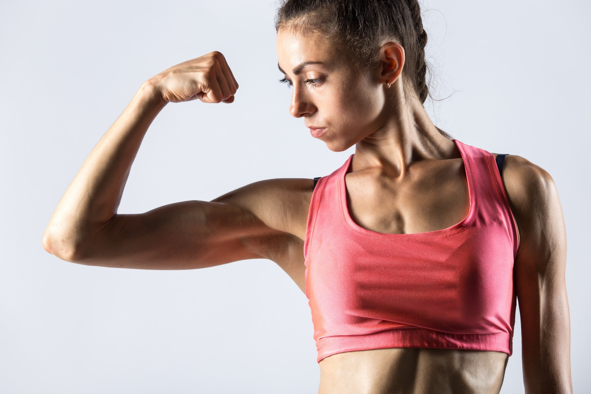 Mulher demonstra músculos do bíceps. 
