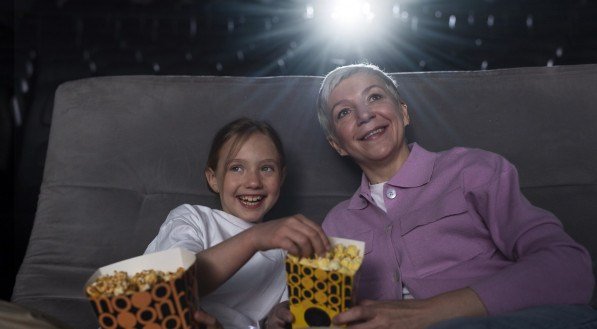 menina e mulher mais velha assistindo a um filme no cinema.
