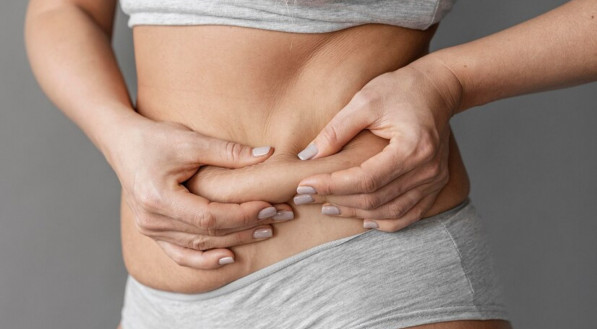 Imagem ilustrativa de uma mulher segurando a gordura da barriga