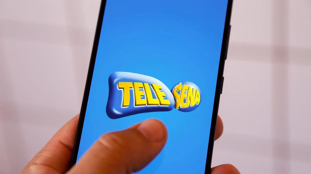 imagem de mão segurando um celular com aplicativo da Tele Sena aberto