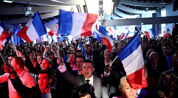Militantes comemoram o anúncio dos resultados da votação durante reunião noturna do partido francês de extrema direita Rassemblement National (RN) no último dia das eleições para o Parlamento Europeu, em Paris