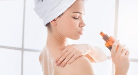 Young female body care at home apply oil