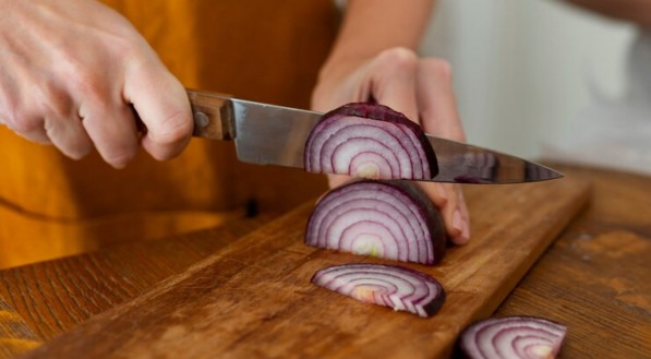 Imagem ilustrativa que mostra pessoa a cortar cebola