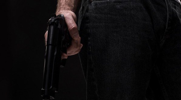 Foto de uma pessoa com uma arma de fogo nas mãos