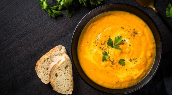 Sopa de abóbora com creme na mesa de pedra preta.