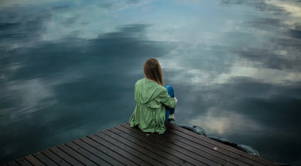 Imagem ilustrativa de uma mulher triste olhando para um lago