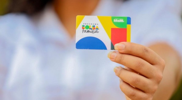 Imagem de beneficiária do Bolsa Família segurando cartão do programa