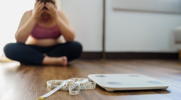 Mulher sentada no chão de casa, com roupa de academia