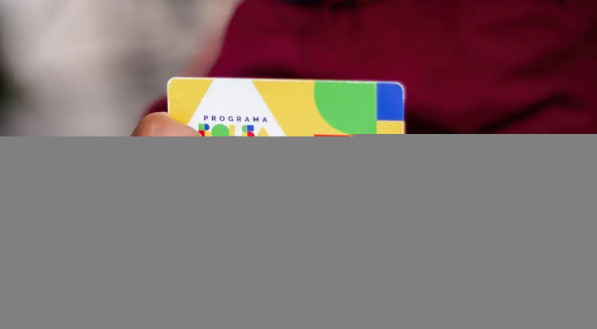 Imagem do cartão do Bolsa Família sendo segurado pelas mãos de um adulto e uma criança