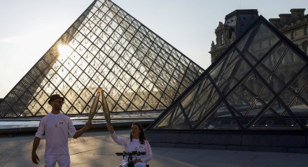 Fotógrafo e artista de rua JR e esquiadora de estilo livre Sandra Laoura no revezamento da tocha olímpica em frente ao museu do Louvre