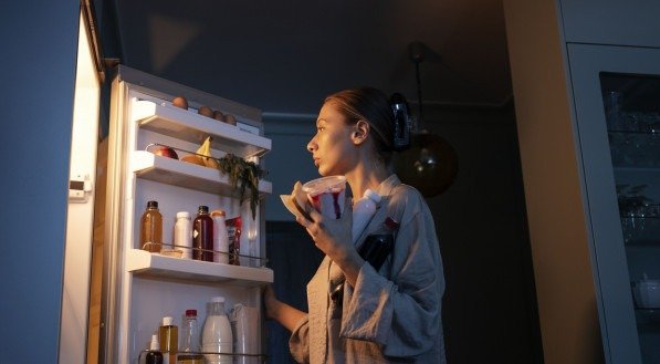 Imagem ilustrativa de uma mulher fazendo um lanche noturno.