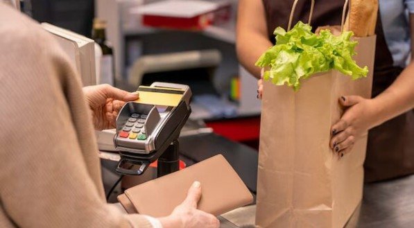 Imagem ilustra um pagamento em supermercado em alusão ao Cartão Alimentação