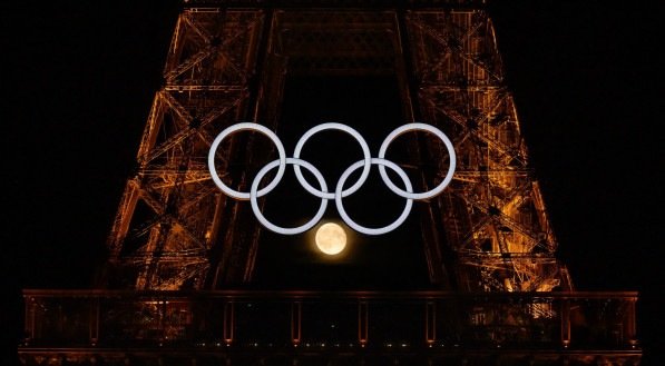 Imagem da Lua em meio aos anéis olímpicos da Torre Eiffel