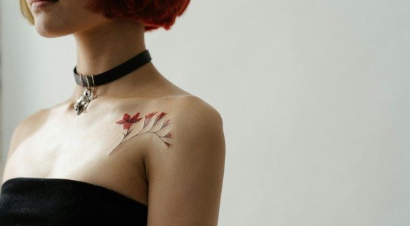 Imagem ilustrativa de mulher de cabelo com tatuagem colorida na clavícula