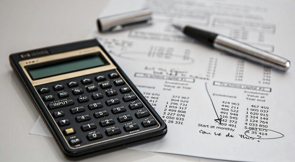 Imagem ilustrativa de calculadora e papéis semelhante a notas
