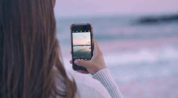 Imagem ilustrativa de uma mulher tirando foto na praia 