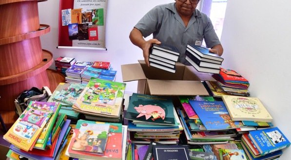 Imagem de senhor com vários livros para doação para o RG