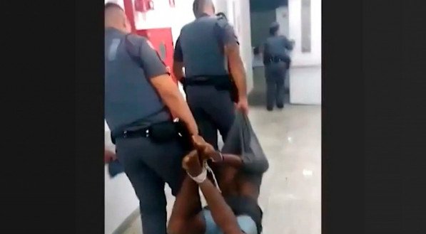 Imagem do suspeito sendo carregado em situação que lembra o método de tortura conhecido por pau-de-arara 