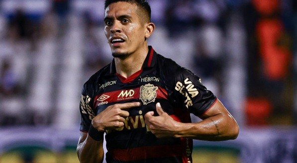 Igor Carius segurando a camisa do Sport e apontando para o escudo do clube Rubro-Negro