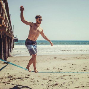 Imagem: Homem praticando slackline na praia