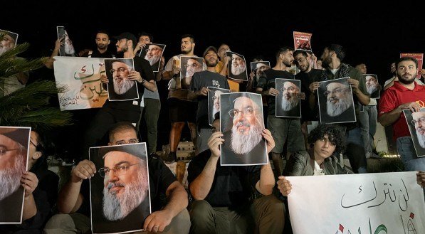 Manifestantes seguram fotos de Hassan Nasrallah, falecido líder do grupo libanês Hezbollah, durante uma vigília de protesto na cidade de Sidon, no sul do Líbano, em 28 de setembro de 2024