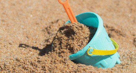 Imagem: Balde de plástico, brinquedo de criança, na areia da praia