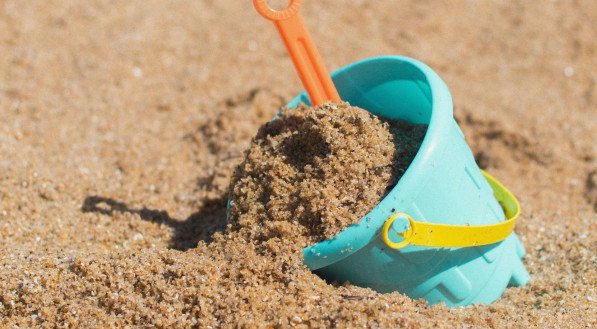 Imagem: Balde de plástico, brinquedo de criança, na areia da praia