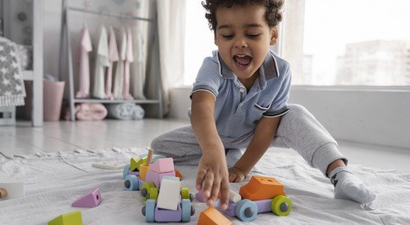 Imagem ilustrativa: criança brincando com carrinhos e blocos de montar.