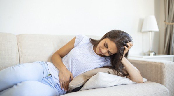 Imagem: mulher com fortes cólicas, sintoma comum da endometriose.