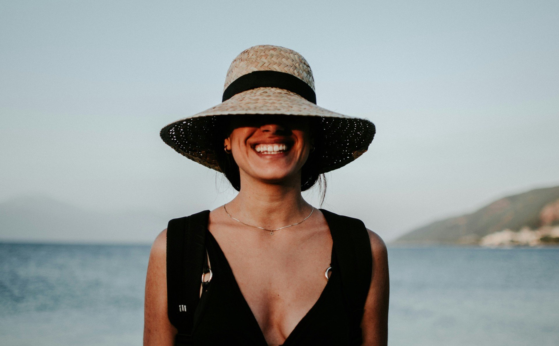 Imagem ilustrativa de uma mulher sorrindo, enquanto viaja para a praia